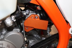 Detailaufnahme eines orangefarbenen Motorradbauteils an einem KTM-Motor, das für Leistung und Zuverlässigkeit sorgt.