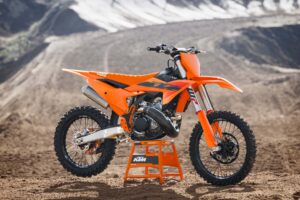 Eine KTM Motocross-Maschine steht auf einem Ständer in einer sandigen Umgebung, ideal für Offroad-Abenteuer und sportliche Herausforderungen.