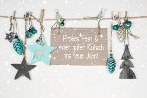 Festliche Dekoration mit Weihnachtsbaum-Schmuck und einem Schild, das frohe Festtagsgrüße und einen guten Rutsch ins neue Jahr wünscht.